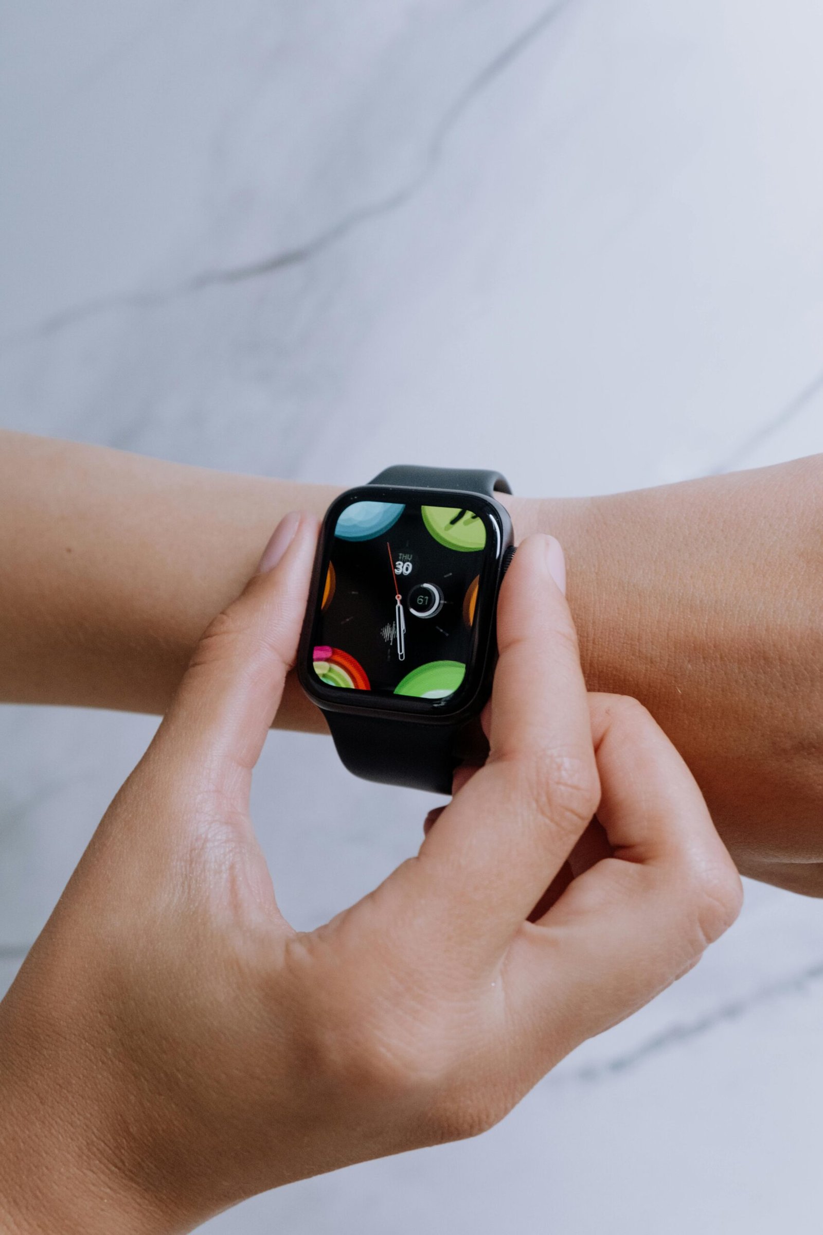 Modern smartwatch displayed on wrist with a decorative marble background, showcasing vibrant touchscreen and technology.